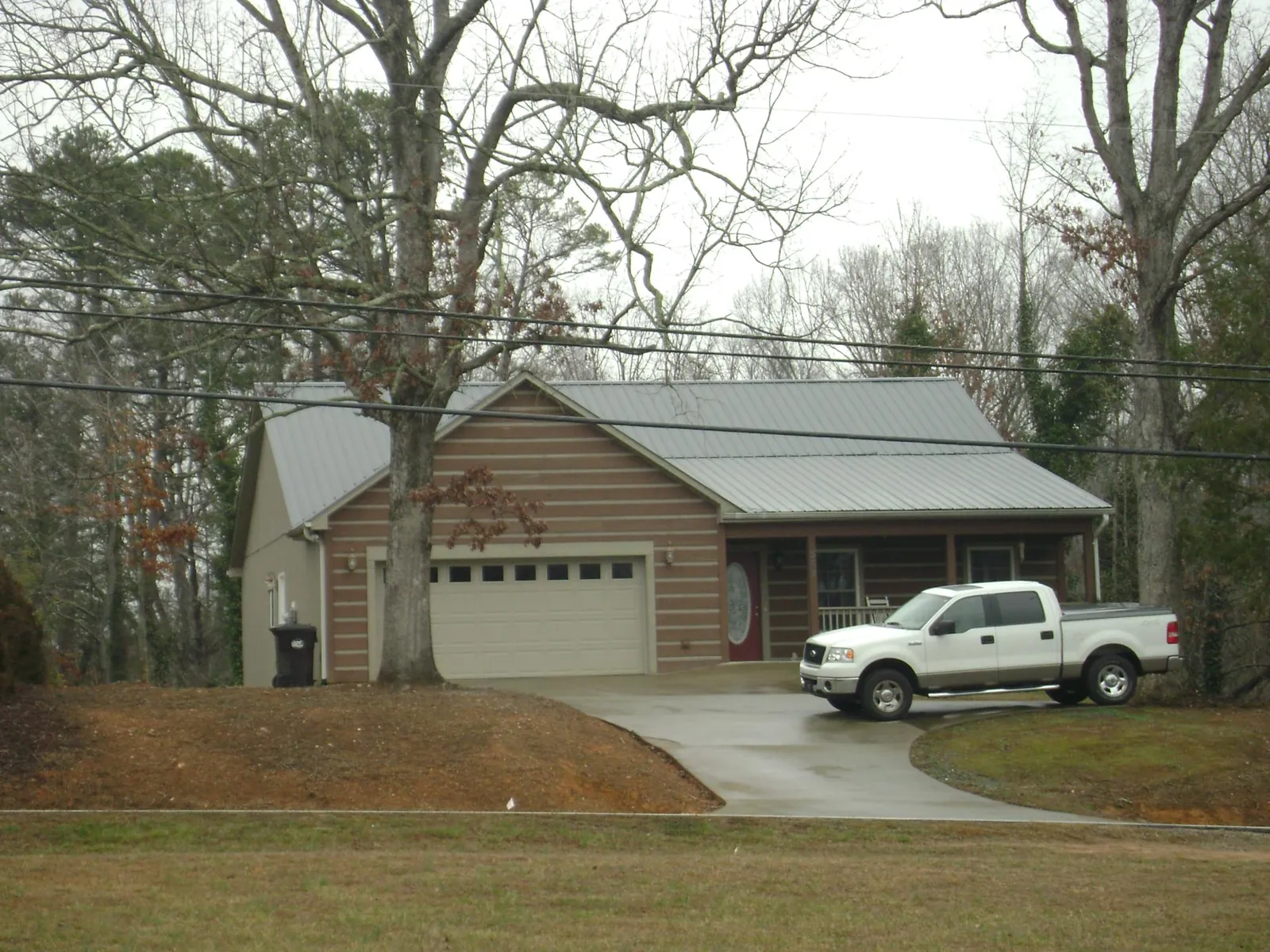 Gray metal roof on a log sided house with an attached two car garage in Westwood