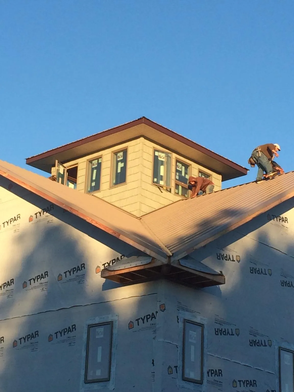 Roofers working around a rooftop cupola on a new metal roof at sunset — Roof Waterproofing in Westwood by Roofing Brothers